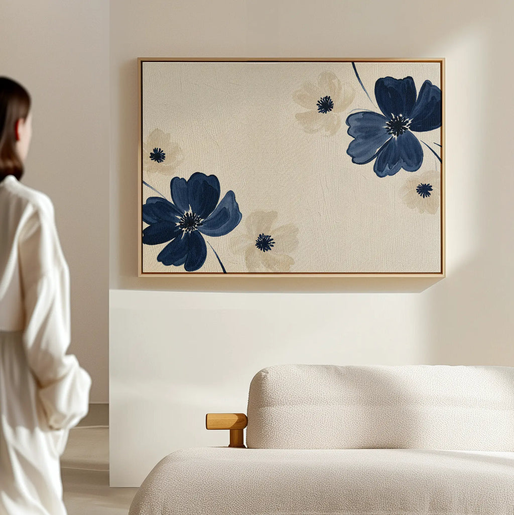A person stands near a light-colored sofa, admiring the Midnight Garden Canvas Art—a large, modern floral painting in blue and beige—adding elegance to the softly lit, minimalist room.