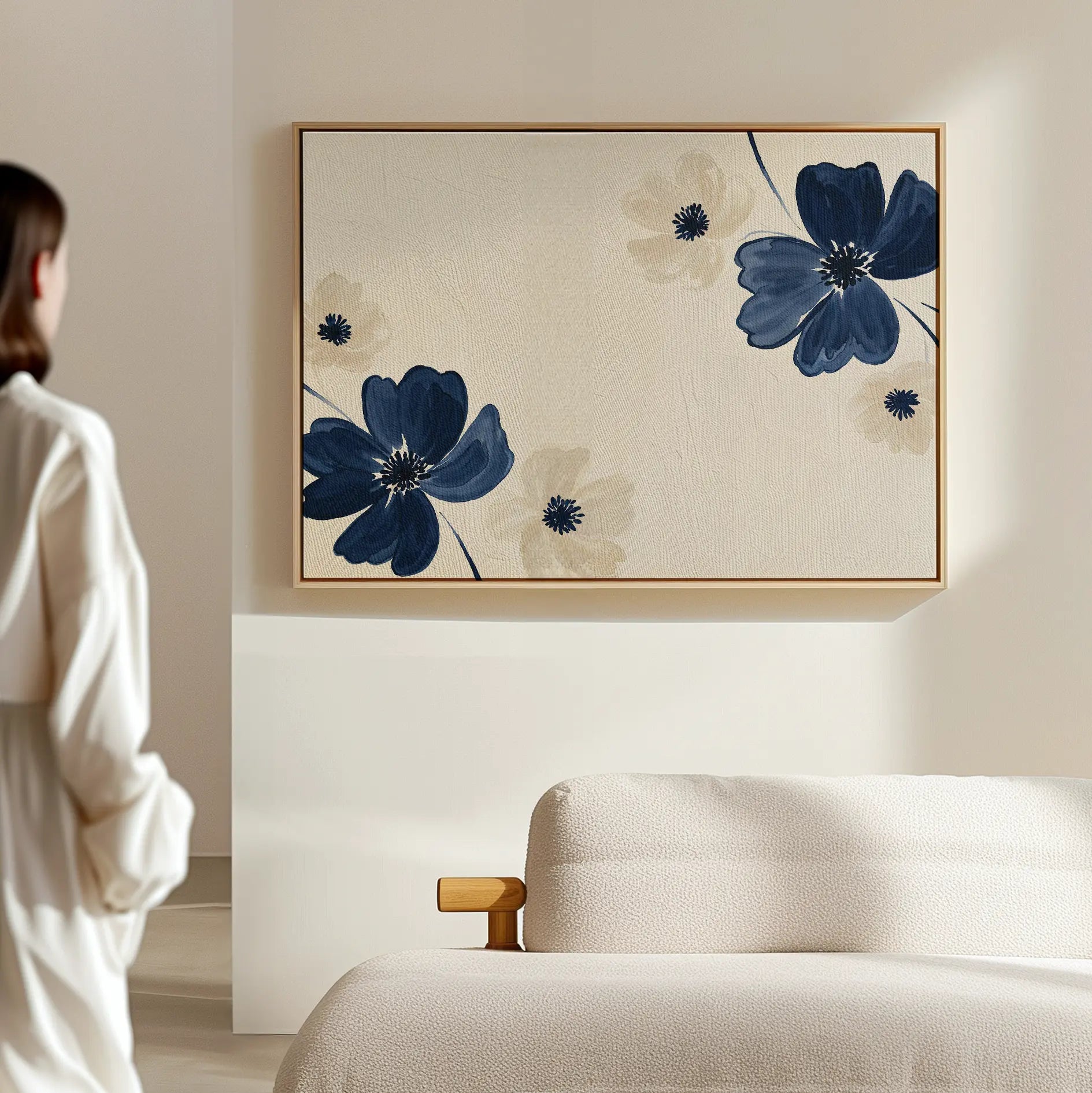 A person stands near a light-colored sofa, admiring the Midnight Garden Canvas Art—a large, modern floral painting in blue and beige—adding elegance to the softly lit, minimalist room.