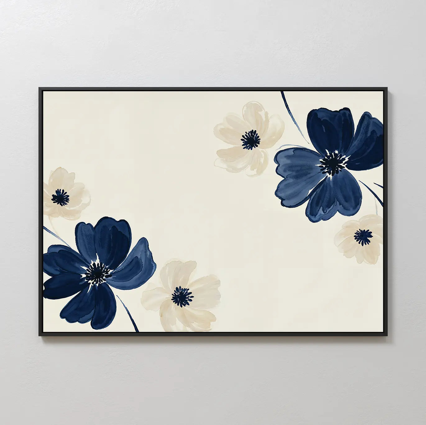 The Midnight Garden Canvas Art features large navy blue and light beige flowers with dark centers on a cream background, arranged diagonally for a striking modern look and framed in black.