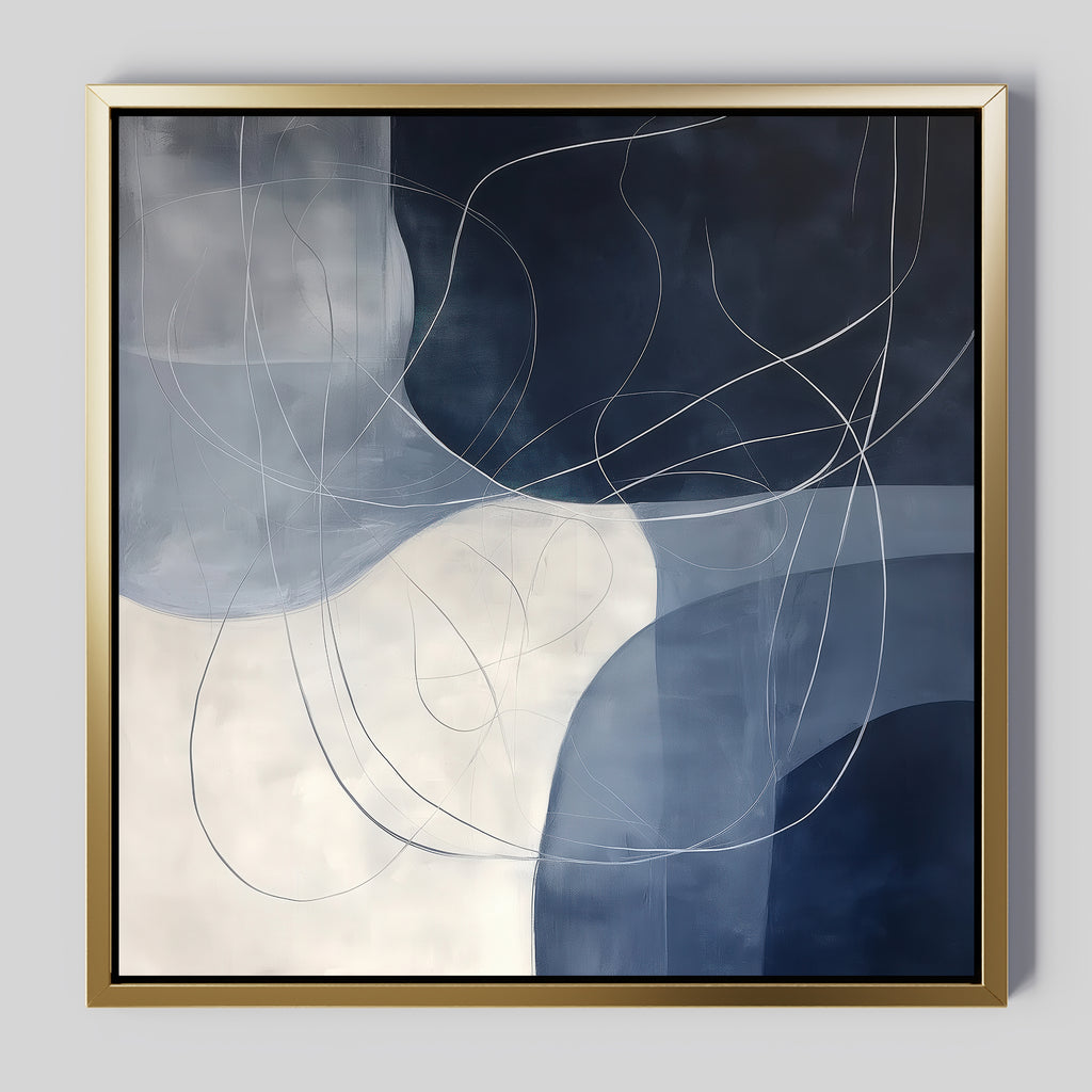 Midnight Lines Abstract Canvas Art features overlapping blue, white, and gray shapes with sweeping white lines. Framed in gold on a light gray background, its a stylish wall art piece ideal for modern living room decor.