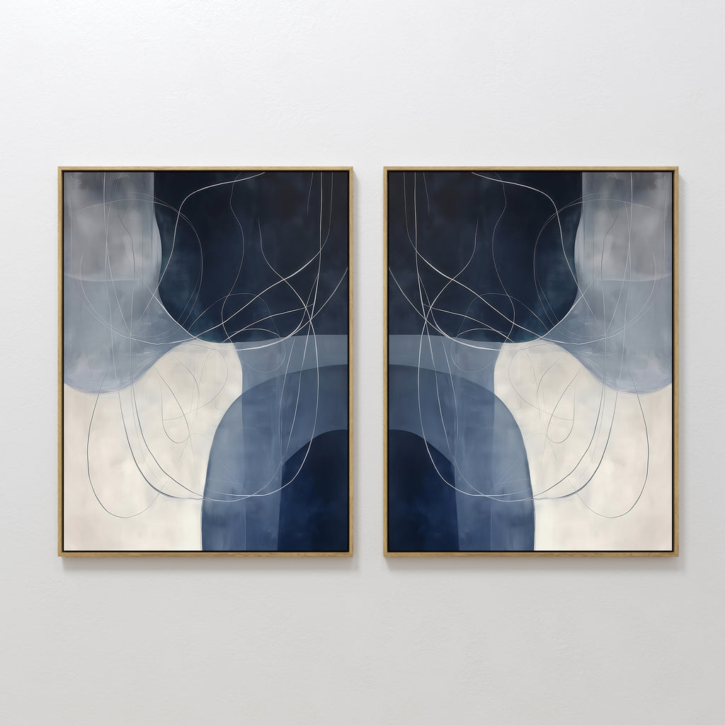 The Midnight Lines Set of 2 features abstract paintings in gold frames with overlapping blue, gray, and white shapes and thin swirling lines, embodying minimalist and modern wall art when displayed side by side.