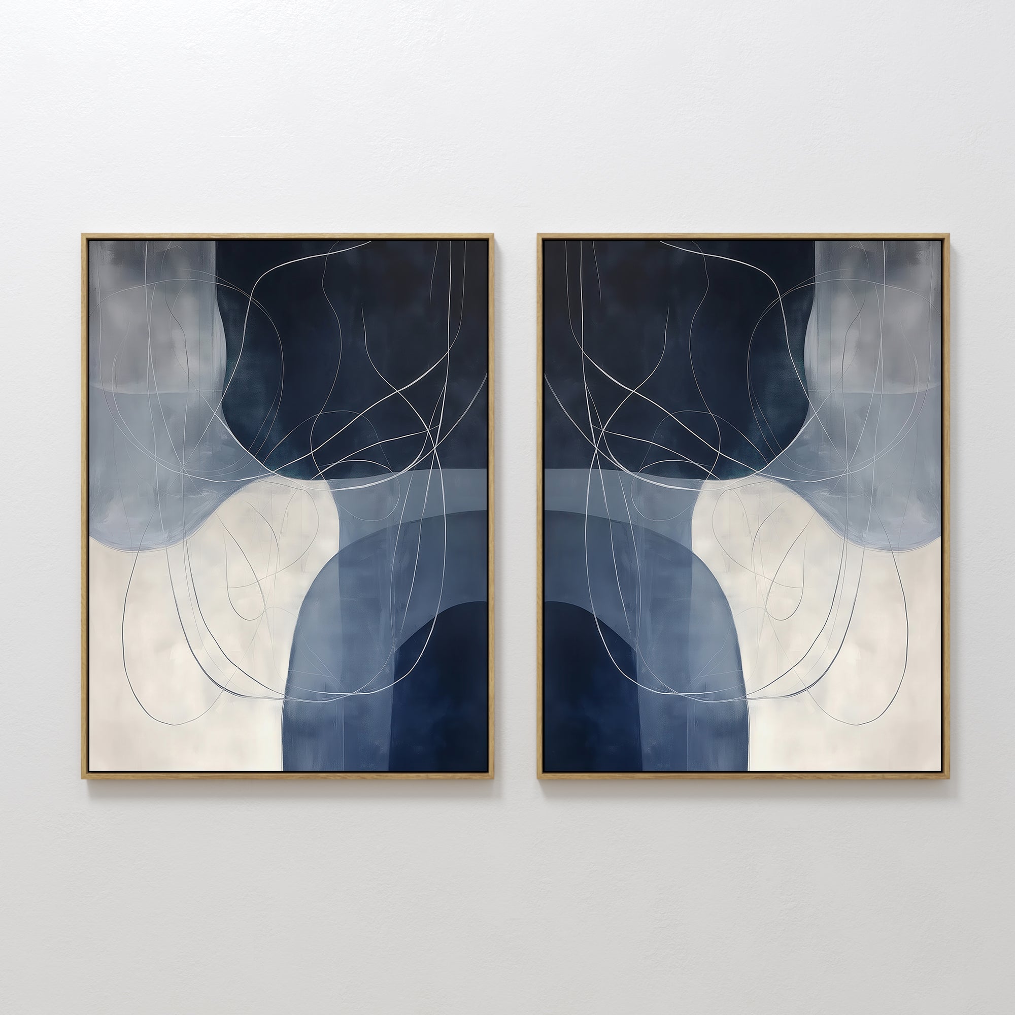 The Midnight Lines Set of 2 features abstract paintings in gold frames with overlapping blue, gray, and white shapes and thin swirling lines, embodying minimalist and modern wall art when displayed side by side.