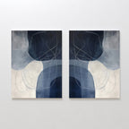 The "Midnight Lines Set of 2" features abstract minimalist wall art in cool blue, gray, and white tones, with curved shapes and looping lines forming a mirrored, symmetrical composition for a modern, elegant look.