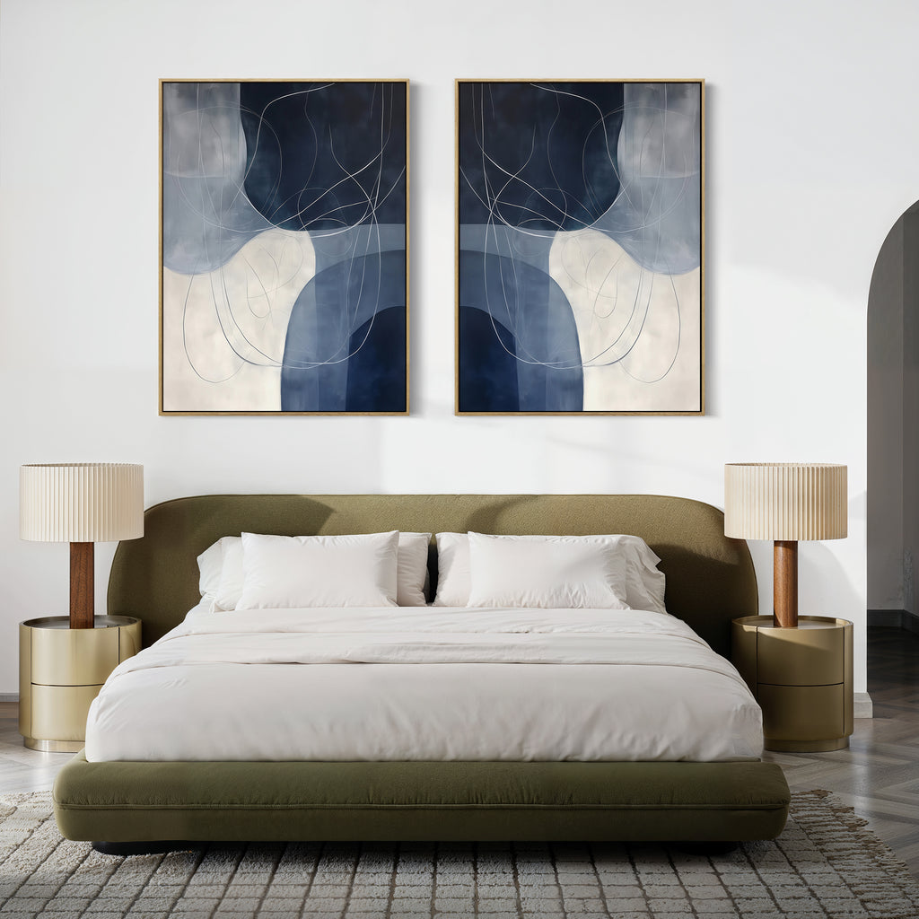 A modern bedroom featuring an olive green upholstered bed, white bedding, two round beige nightstands with pleated lamps, and the Midnight Lines Set of 2 blue and white abstract paintings above the headboard. A textured rug completes the look.