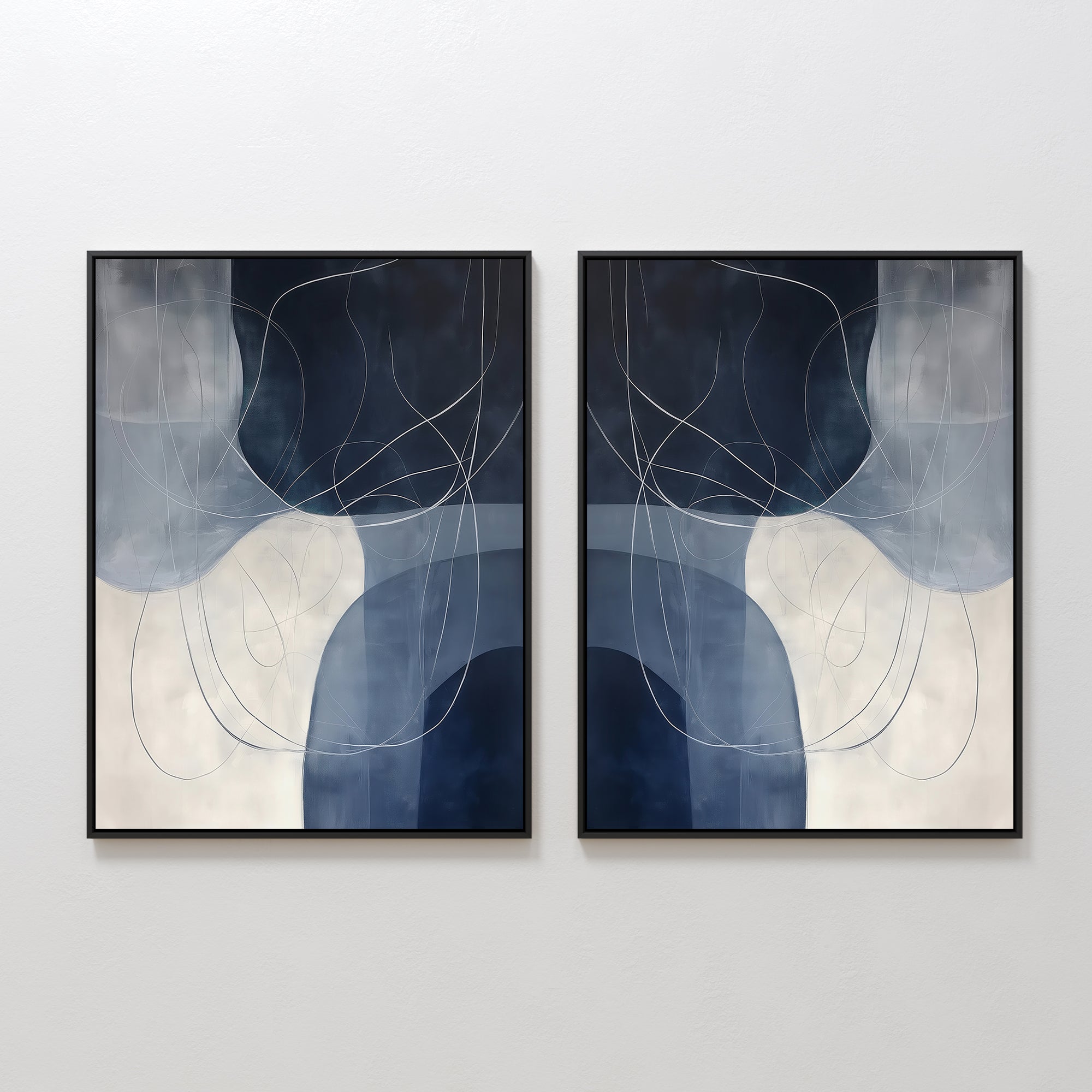 The Midnight Lines Set of 2 features abstract paintings in black frames with overlapping dark blue, gray, and white shapes accented by thin, curved lines, creating a modern, elegant look on any wall.