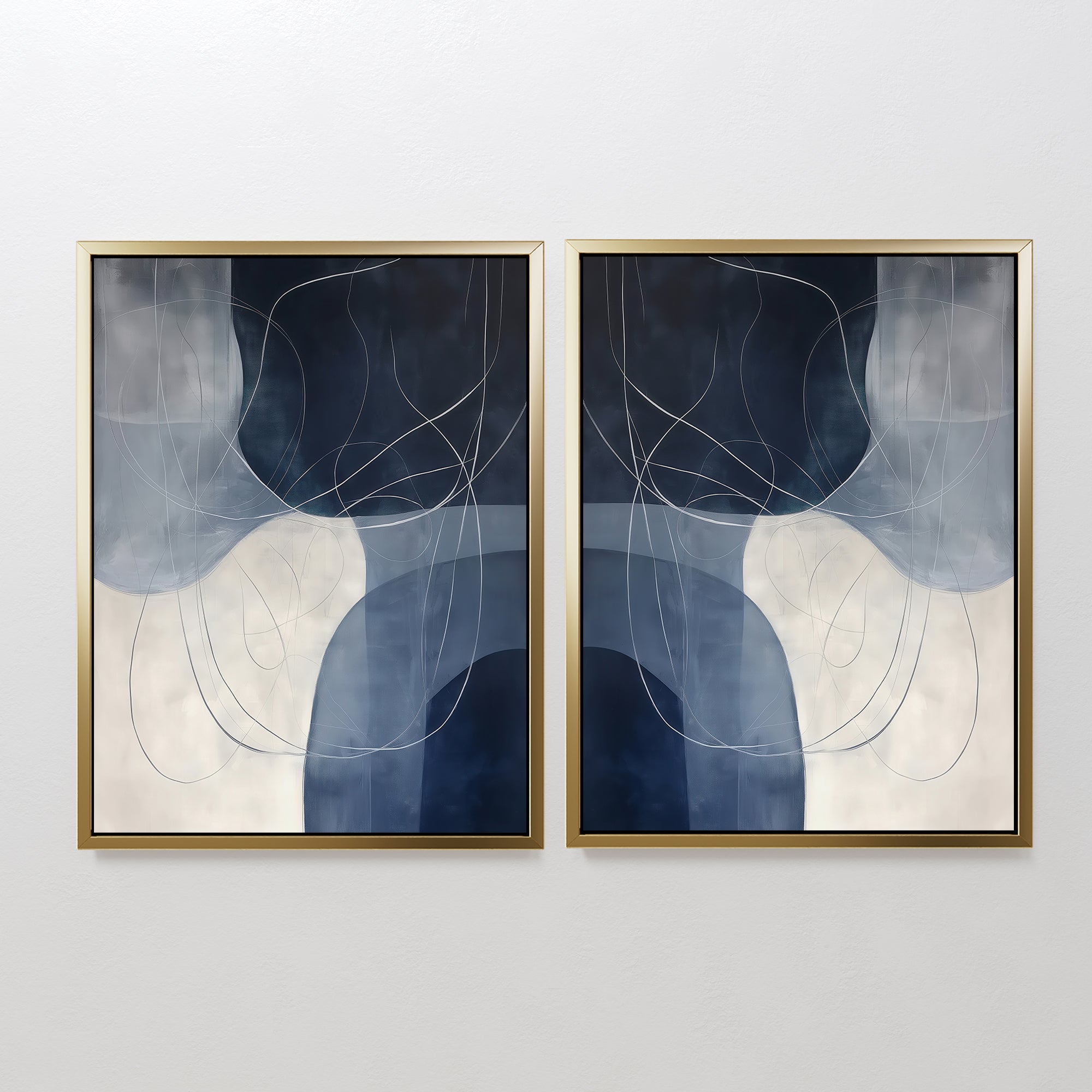 The Midnight Lines Set of 2 features abstract gold-framed paintings with overlapping blue, gray, and white shapes accented by thin curving lines, creating a mirrored modern design that adds elegance to any white wall.