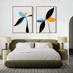 A modern bedroom with a green upholstered bed, beige nightstands with matching lamps, and the Minimal Flora Set of 2 wall art—abstract floral prints in blue, orange, and black—displayed above the bed for a stylish touch.