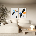 A modern living room with a beige sectional sofa, wooden coffee table, round lamp, books, indoor plant, and Minimal Flora Set of 2 wall art featuring abstract floral prints in black, blue, and orange shapes on the wall.