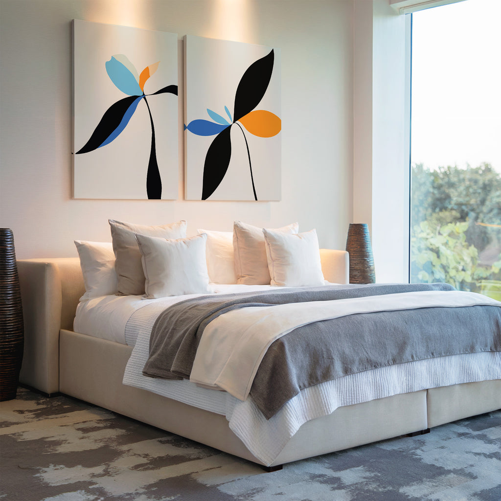 A modern bedroom with a large neutral-toned bed, several white pillows, the Minimal Flora Set of 2 wall art above the headboard, floor vases on either side, and a big window showing lush greenery outside.
