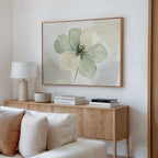 Minimalist living room with a light wood sideboard, white lamp, stacked books, small bowl, and the Mint Meadow Canvas Art featuring green and cream flowers above. A white sofa is in the foreground.