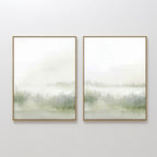 The Misty Forest Set of 2 features framed watercolor prints in soft green and gray, depicting abstract trees fading into a cloudy sky—ideal for adding serene elegance to any room.