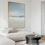 A modern living room with a cream chaise lounge, black round coffee table, cup, two candle holders, and the Misty Morning Canvas Art – Vertical on a white paneled wall creates a tranquil atmosphere inspired by Nordic Park.