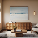 A minimalist living room features a modern wooden sideboard, low coffee table, light sofa, and coastal accents. The Misty Morning Canvas Art – Horizontal above the sideboard and soft lighting create a calm, inviting atmosphere.