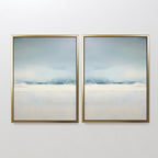 The Misty Morning Set of 2 features framed abstract art in soft blue, white, and beige tones. Their minimalist design with mirrored horizon lines evokes serene seascapes or landscapes, creating a tranquil atmosphere on any white wall.