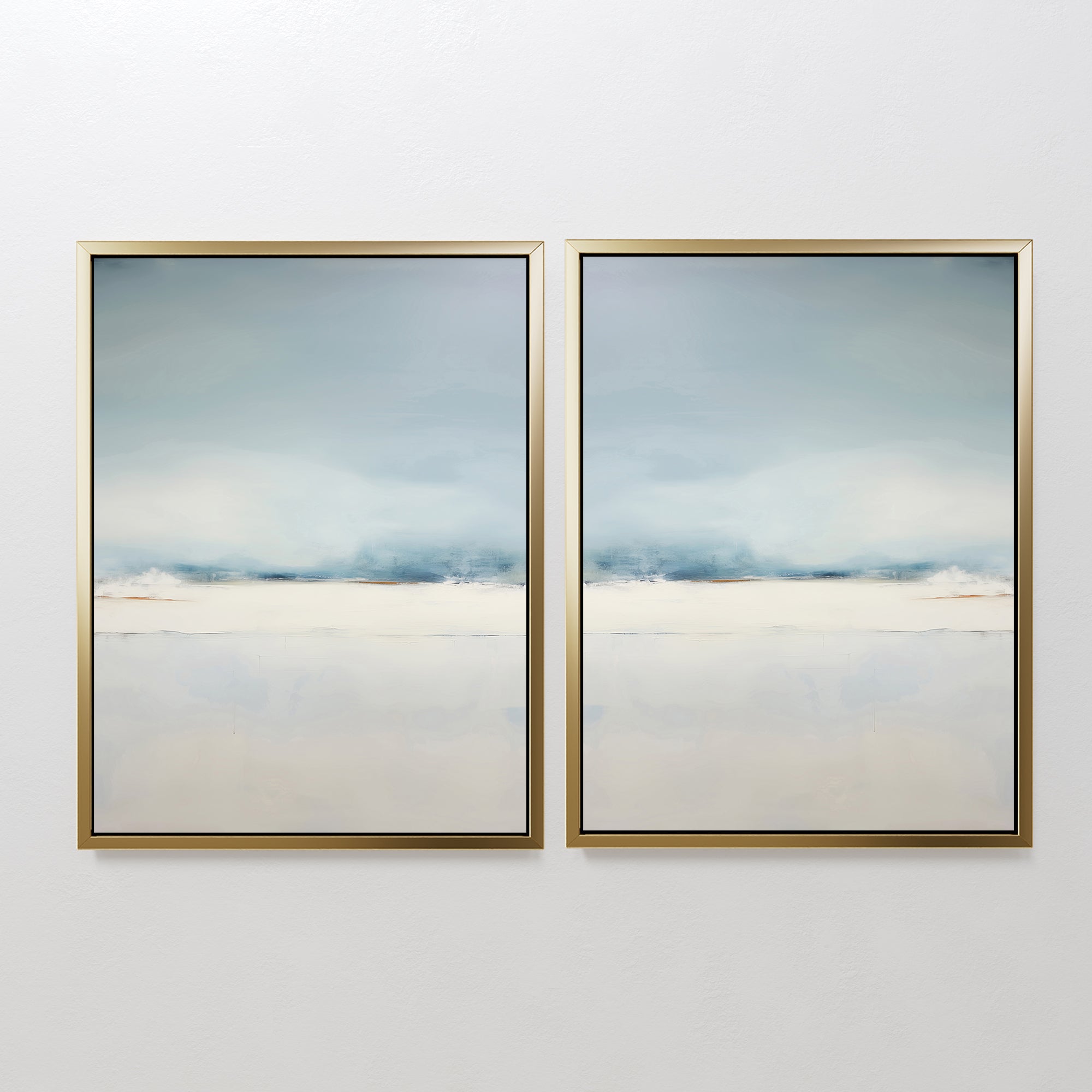 The Misty Morning Set of 2 features framed abstract art in soft blue, white, and beige tones. Their minimalist design with mirrored horizon lines evokes serene seascapes or landscapes, creating a tranquil atmosphere on any white wall.