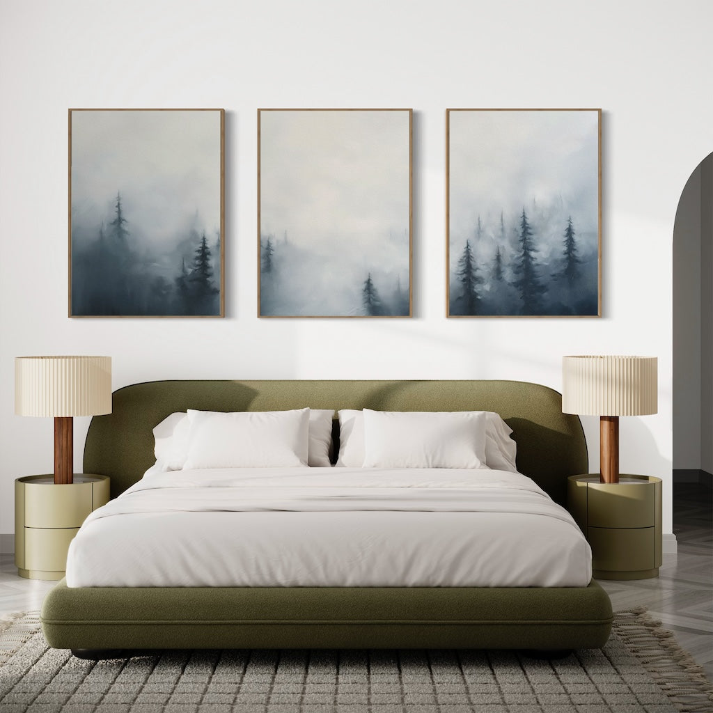 A modern bedroom features an olive green bed, white bedding, beige lamps on round nightstands, and the Misty Pines Set of 3—three framed paintings of misty pine trees—displayed above the bed.