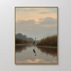 The Misty Reflection Canvas Art features a heron standing in shallow water at sunset, surrounded by grasses and trees. Soft clouds and muted colors create a peaceful scene, making it perfect wall art for a calming atmosphere.