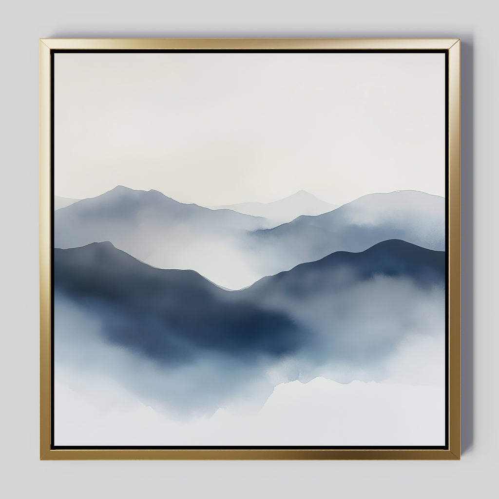 Misty Ridge Canvas Art features a minimalist landscape of blue and gray misty mountains fading into a pale sky, set on a large canvas with a sleek gold frame, perfect for display on any light gray wall.