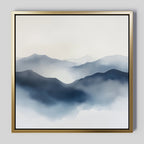 Misty Ridge Canvas Art features a minimalist landscape of blue and gray misty mountains fading into a pale sky, set on a large canvas with a sleek gold frame, perfect for display on any light gray wall.