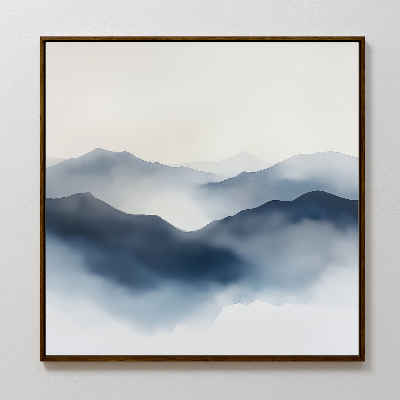 The Misty Ridge Canvas Art features a minimalist landscape of misty blue mountains with soft, layered peaks fading into a pale sky. This abstract wall art is framed in a thin brown frame and displayed on a white wall.