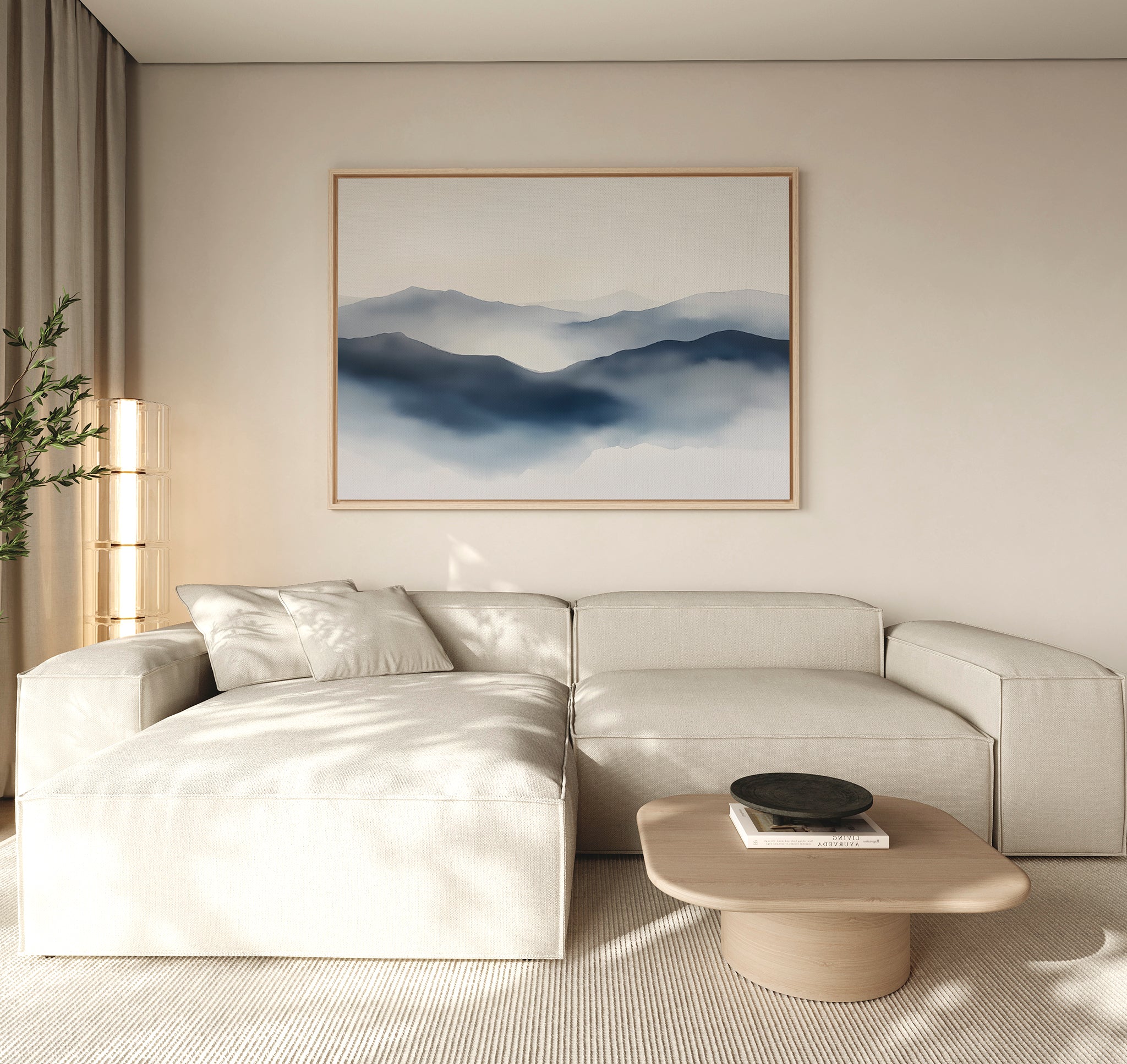 A minimalist living room with a light beige sectional sofa, low wooden coffee table, potted plant, and a Misty Ridge Canvas Art – Horizontal depicting blue mountains on a neutral wall.