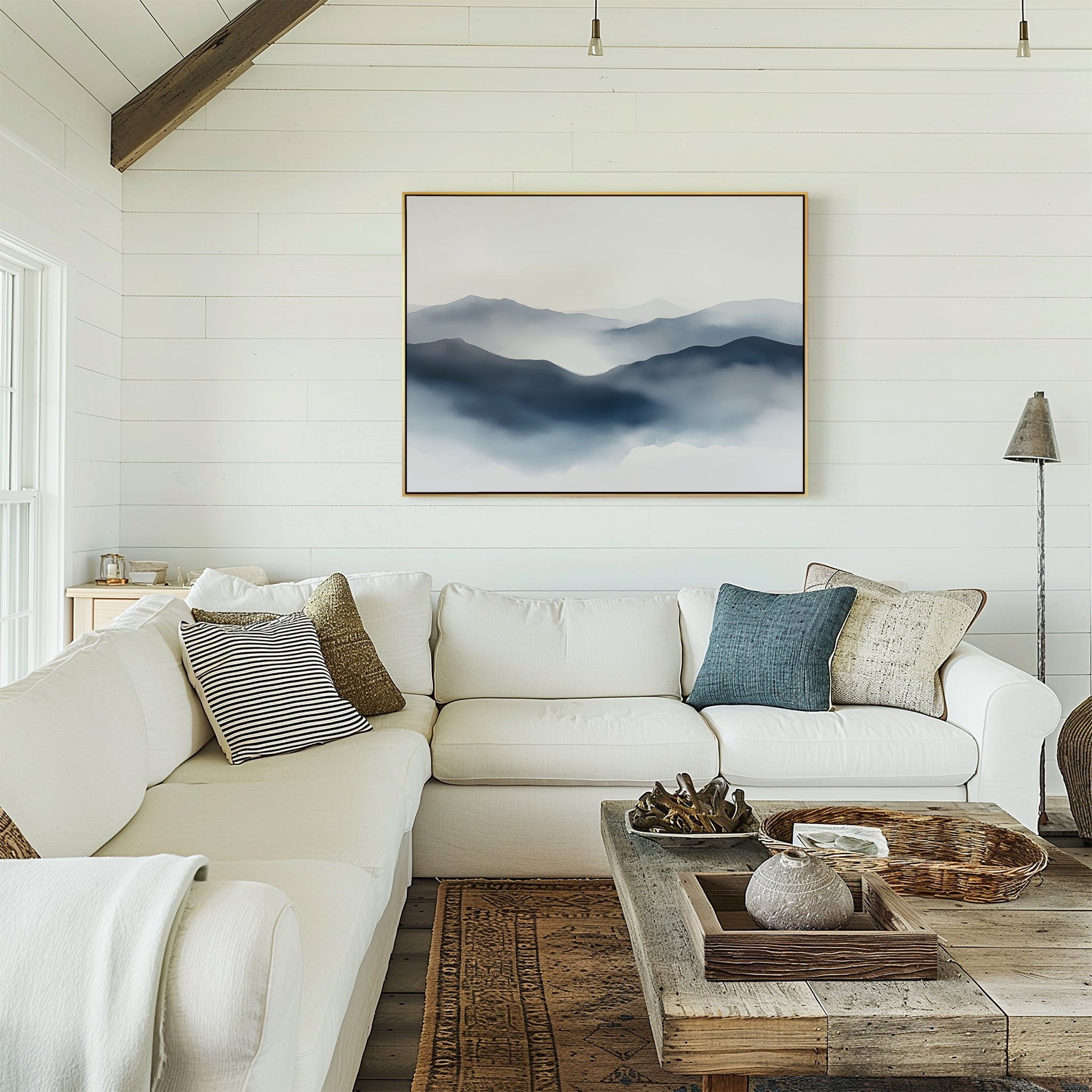 A bright living room with white shiplap walls, a white sectional sofa with pillows, a rustic wood coffee table, and the Misty Ridge Canvas Art – Horizontal hanging above the couch.