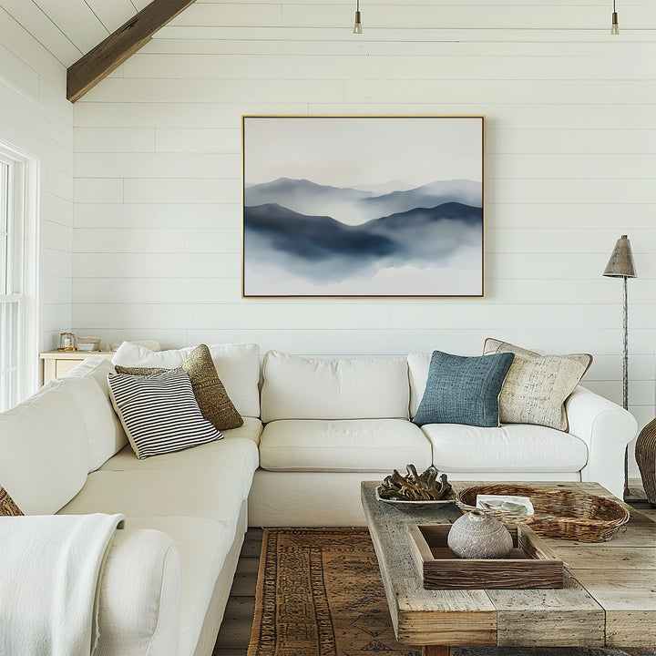 A bright living room with white shiplap walls, a white sectional sofa with pillows, a rustic wood coffee table, and the Misty Ridge Canvas Art – Horizontal hanging above the couch.