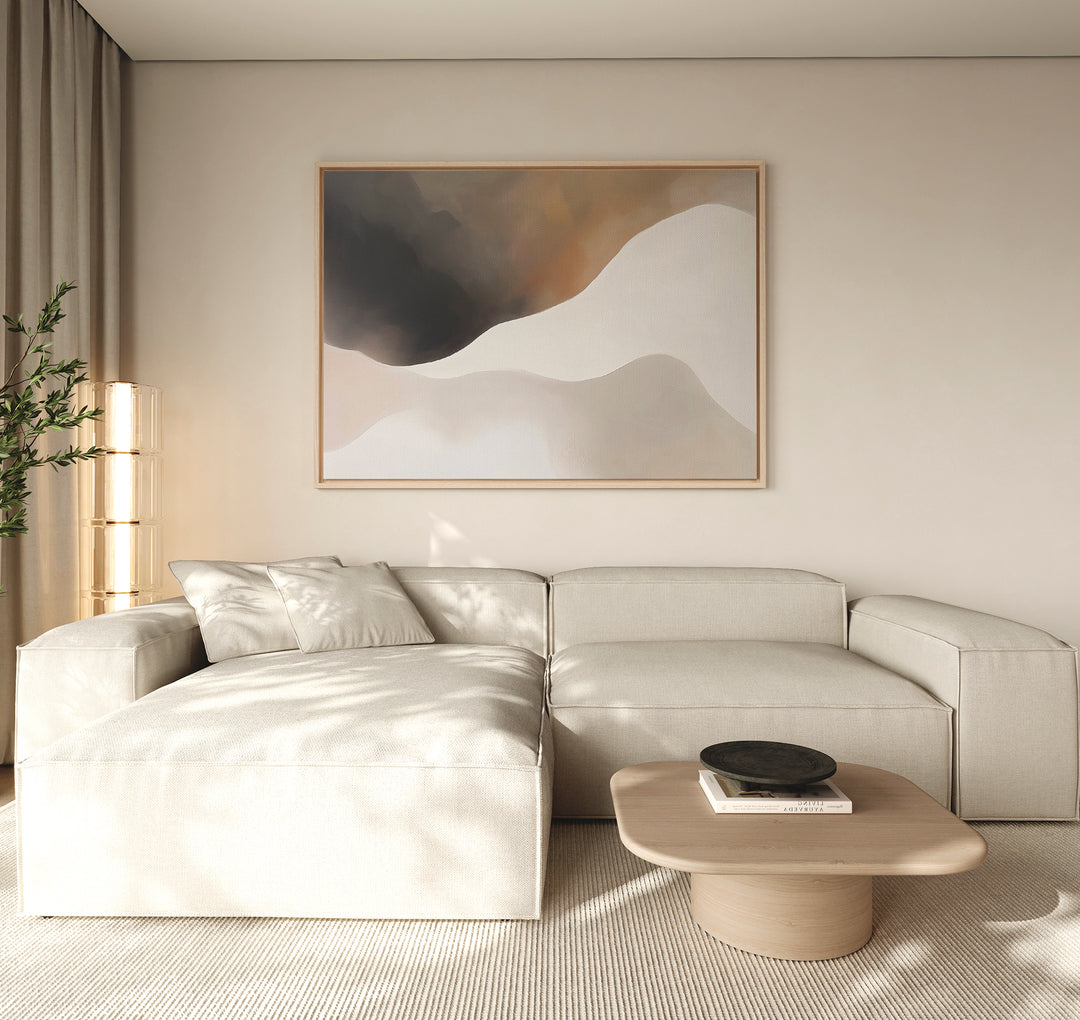 A modern living room with a light beige sectional, wood coffee table with black bowl and books, beige curtains, a tall plant in the corner, and Misty Silhouette Canvas Art – Horizontal as the focal point for refined decor.
