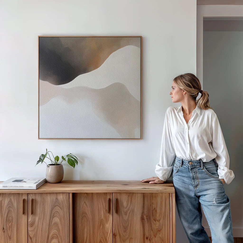 A woman leans on a cabinet in a modern living room, highlighted by the Misty Silhouette Canvas Arts minimalist style on the wall.