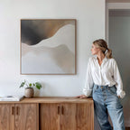 A woman leans on a cabinet in a modern living room, highlighted by the Misty Silhouette Canvas Arts minimalist style on the wall.