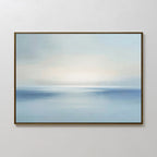 Misty Waters Canvas Art is a framed abstract painting in soft blues and whites, evoking a tranquil seascape with a luminous horizon—ideal for serene or minimalist wall art in modern decor. Shown on a plain white wall.