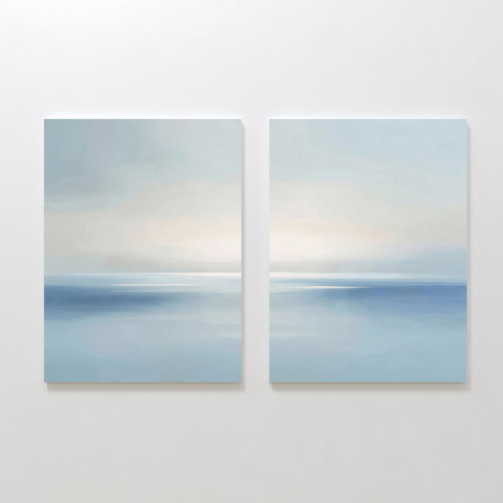 The Misty Waters Set of 2 features minimalist paintings of tranquil seascapes with soft blue tones, calm water, and hazy horizons beneath pastel skies—ideal serene wall art for your space.