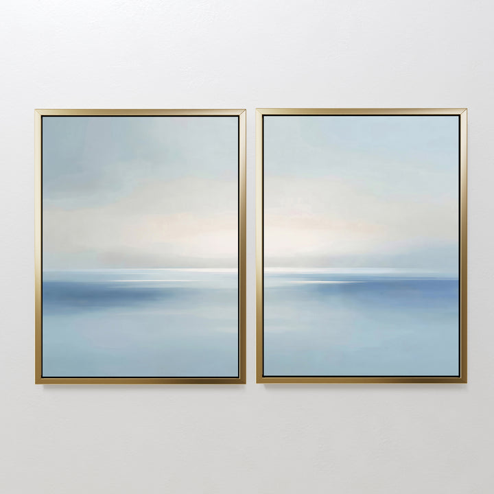 The Misty Waters Set of 2 features modern minimalist wall art—two framed abstract paintings in soft blue and white tones with gentle gradients, evoking a calm seascape. The artworks hang side by side, adding a serene touch to any white wall.