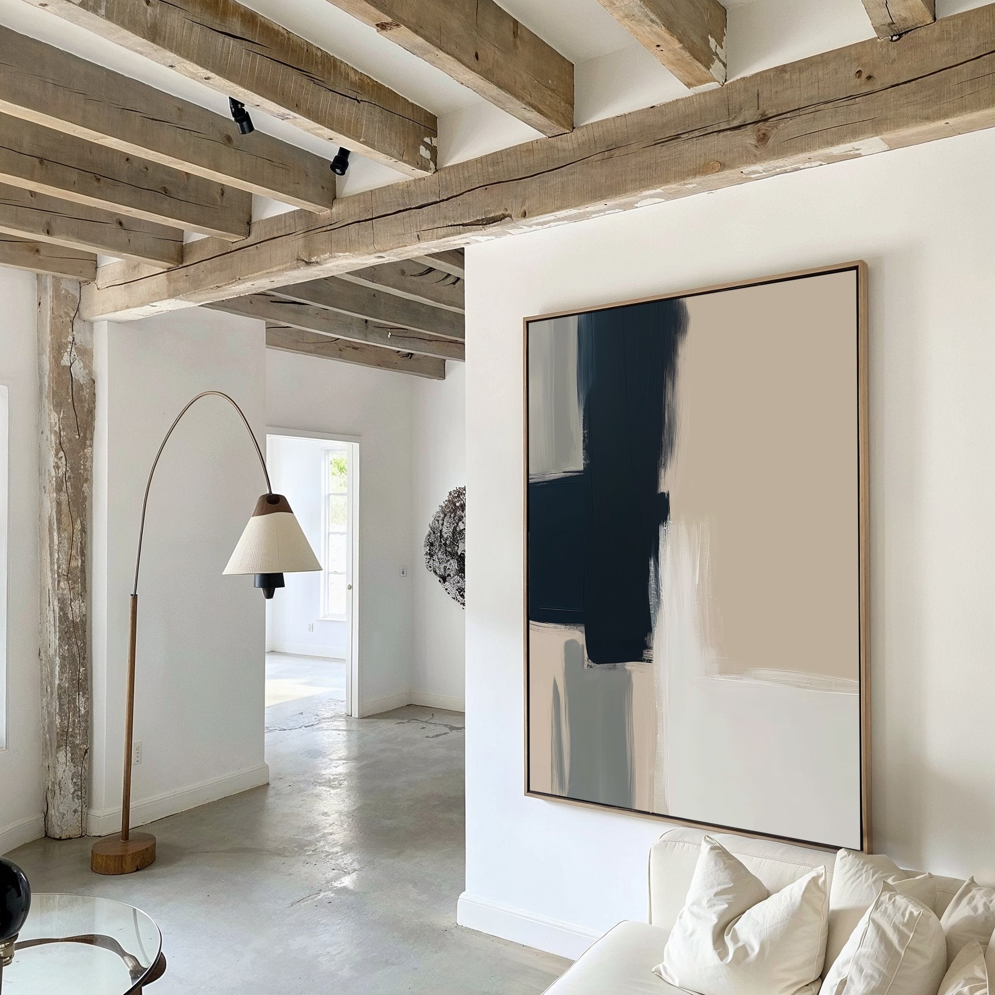 A modern living room with exposed wooden beams, white walls, a curved floor lamp, a white sofa, and the Modern Contrast Abstract Canvas Art. Natural light enters through an open doorway in the background.