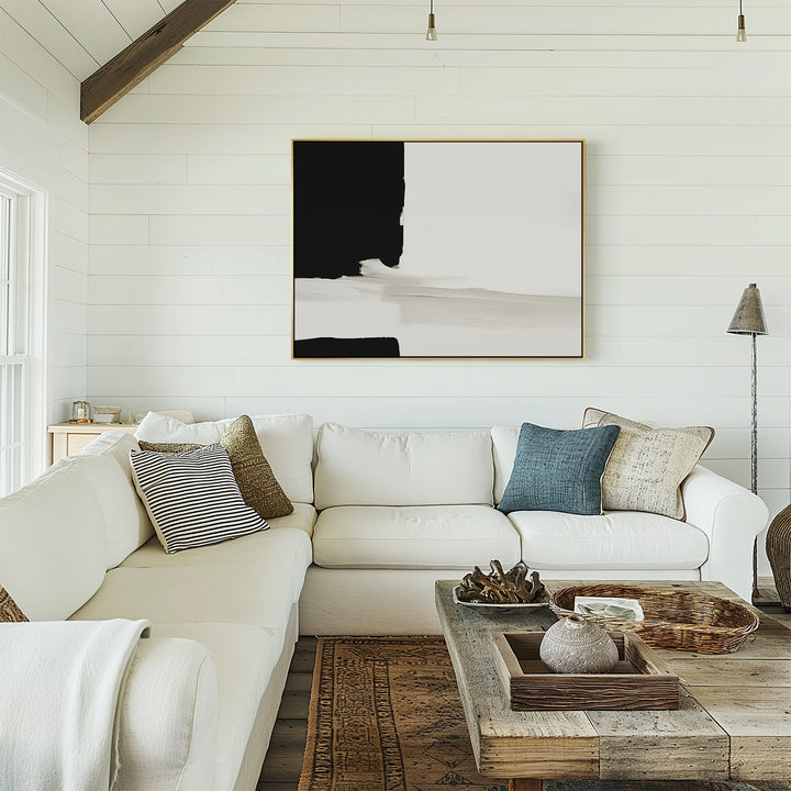 A bright living room with white shiplap walls, a white sectional sofa with assorted pillows, a rustic wooden coffee table, and the Monochrome Harmony Canvas Art – Horizontal displayed above the couch.