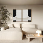 A modern living room with a beige sectional sofa, wooden coffee table with a white lamp and book, an indoor plant, and the Monochrome Harmony Set of 2 minimalist black and white wall art above the sofa.