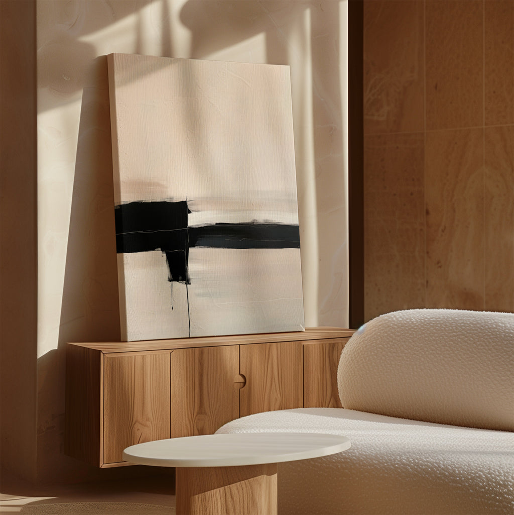 The Monochrome Horizon Abstract Canvas Art, a minimalist piece with a bold black line on a light background, is displayed above a wooden sideboard in a softly lit room with neutral walls and a white textured sofa.