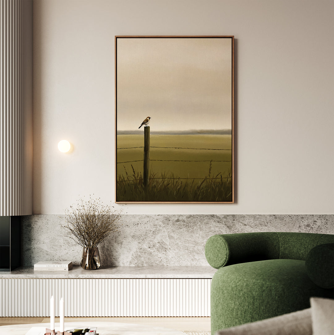 A minimalist living room features a green armchair, marble accents, and the Morning Perch Canvas Art showing a bird on a fence post in a grassy field under a hazy sky—an ideal choice for earthy interiors.