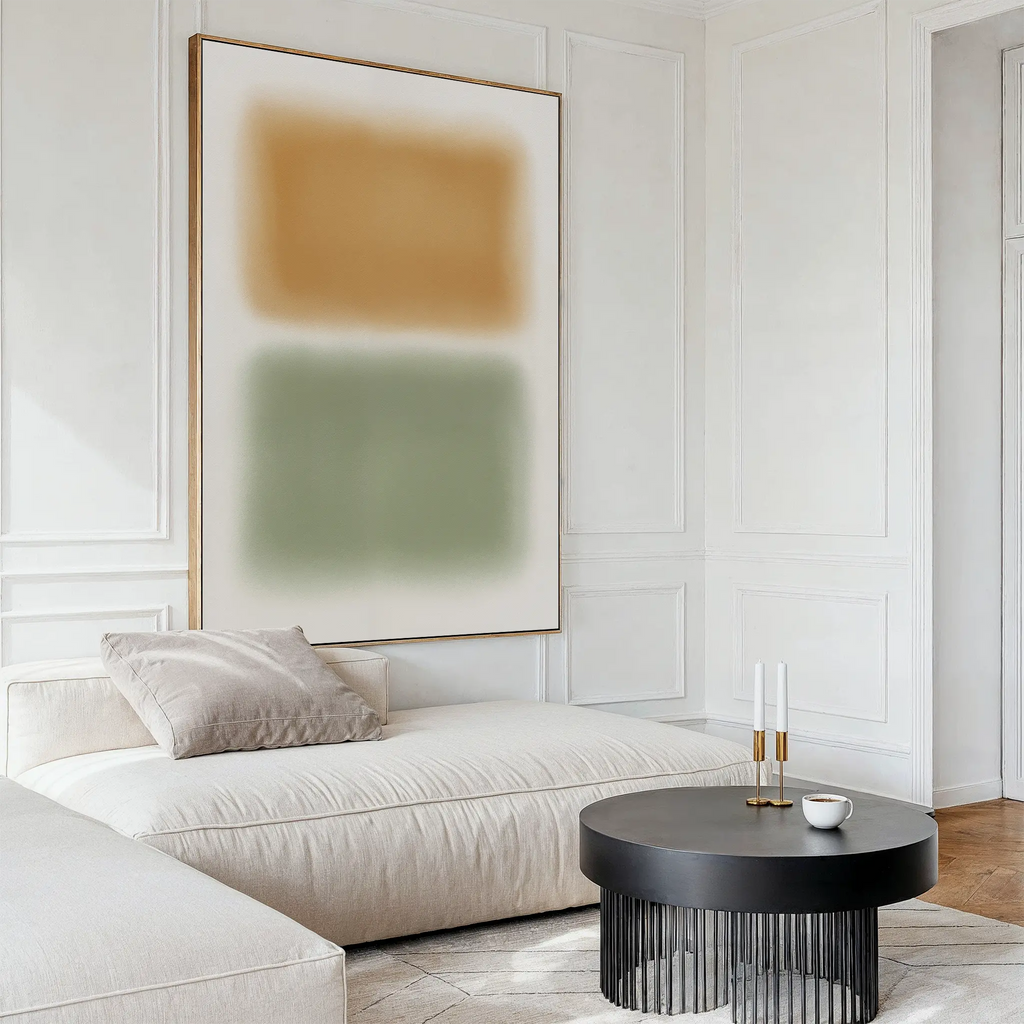 A modern living room featuring Morning Whisper Canvas Art, a cream chaise lounge with pillows, a round black coffee table with candles and a cup, and white paneled walls.