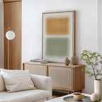 A minimalist living room with a light wooden sideboard, Morning Whisper Canvas Art featuring tan and green blocks, neutral vases, stacked books, a round glass coffee table, a soft white couch, and a leafy plant in the corner.