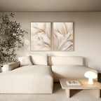 A cozy living room with a beige sectional, a small round lamp on a light wood coffee table, a leafy plant, and the Natural Texture Set of 2 abstract floral wall art bringing minimalist decor to the space.