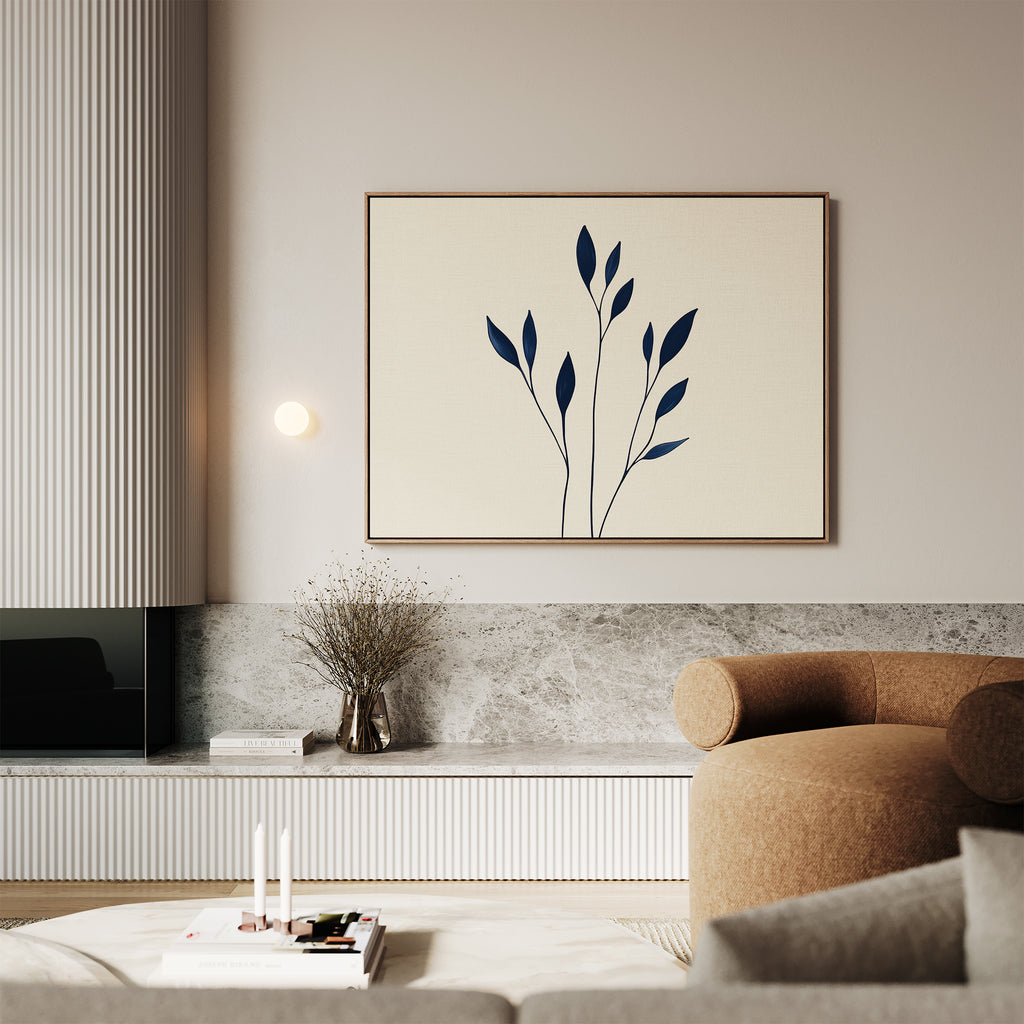 A modern living room features a beige curved sofa, minimalist coffee table, and Navy Stem Canvas Art above a stone shelf with a dried plant in a vase. Neutral tones and modern wall decor create a calm, elegant atmosphere.