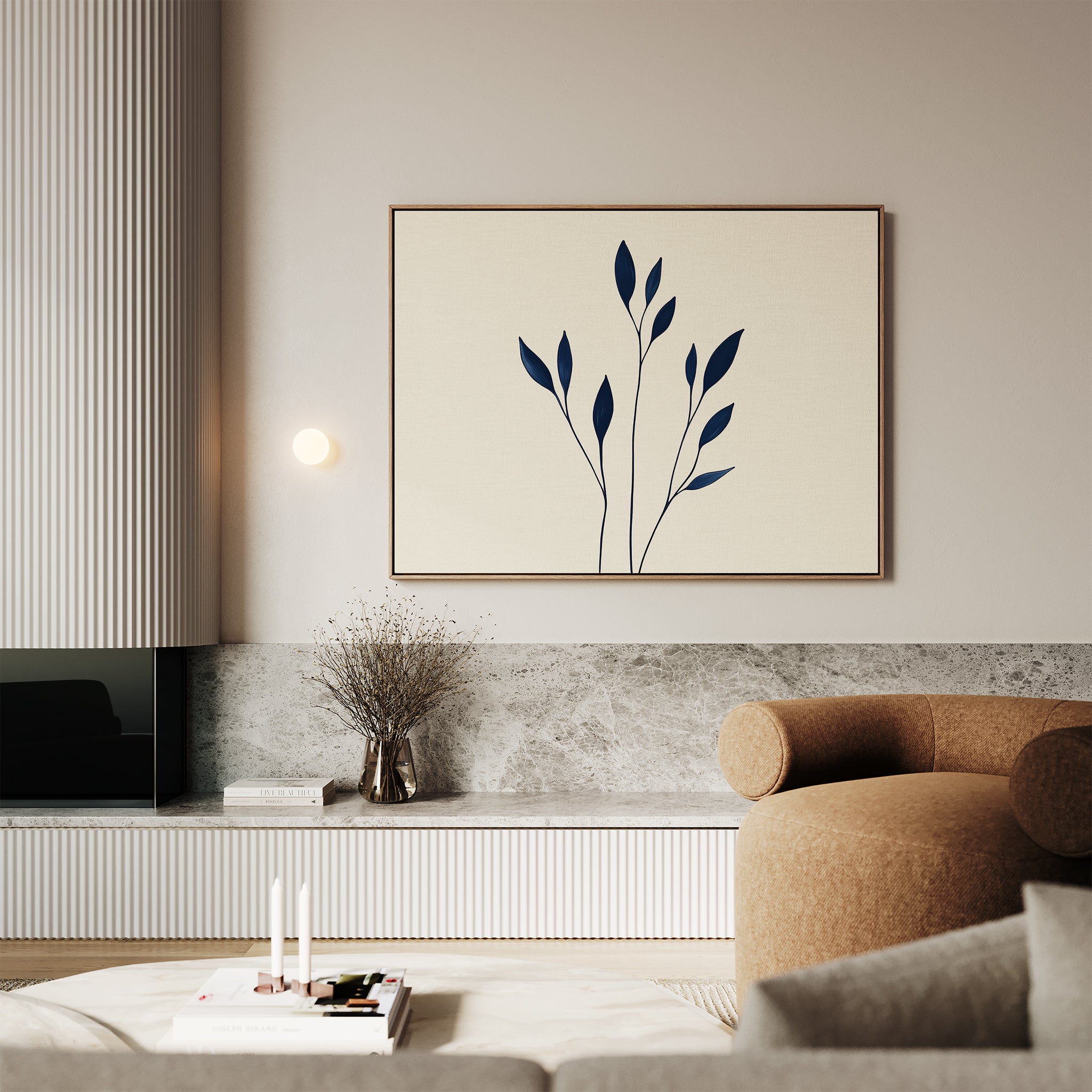 A modern living room features a beige curved sofa, minimalist coffee table, and Navy Stem Canvas Art above a stone shelf with a dried plant in a vase. Neutral tones and modern wall decor create a calm, elegant atmosphere.
