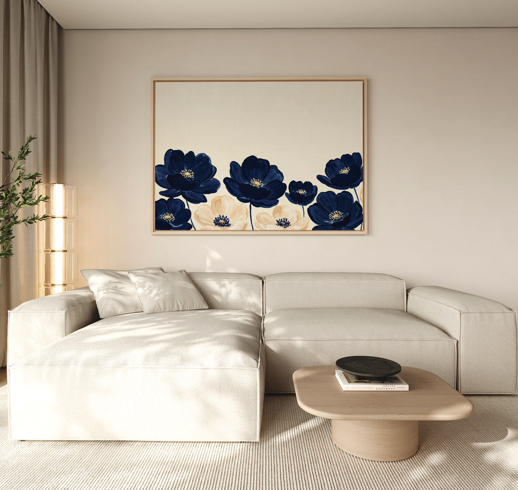 A modern living room with a beige sectional, light wood coffee table, floor lamp, and the Nightshade Canvas Art – Horizontal featuring blue and cream florals. Neutral tones and minimal decor create a calm ambiance.
