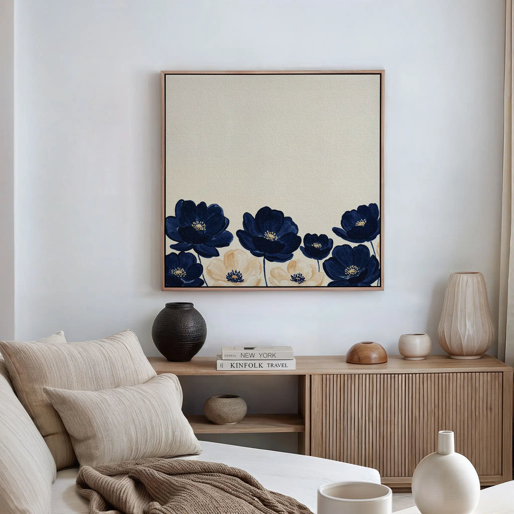 A modern living room with a beige sofa, neutral cushions, and wooden sideboard decorated with vases. Above the sideboard hangs the Nightshade Canvas Art, featuring large navy blue flowers on a cream background.