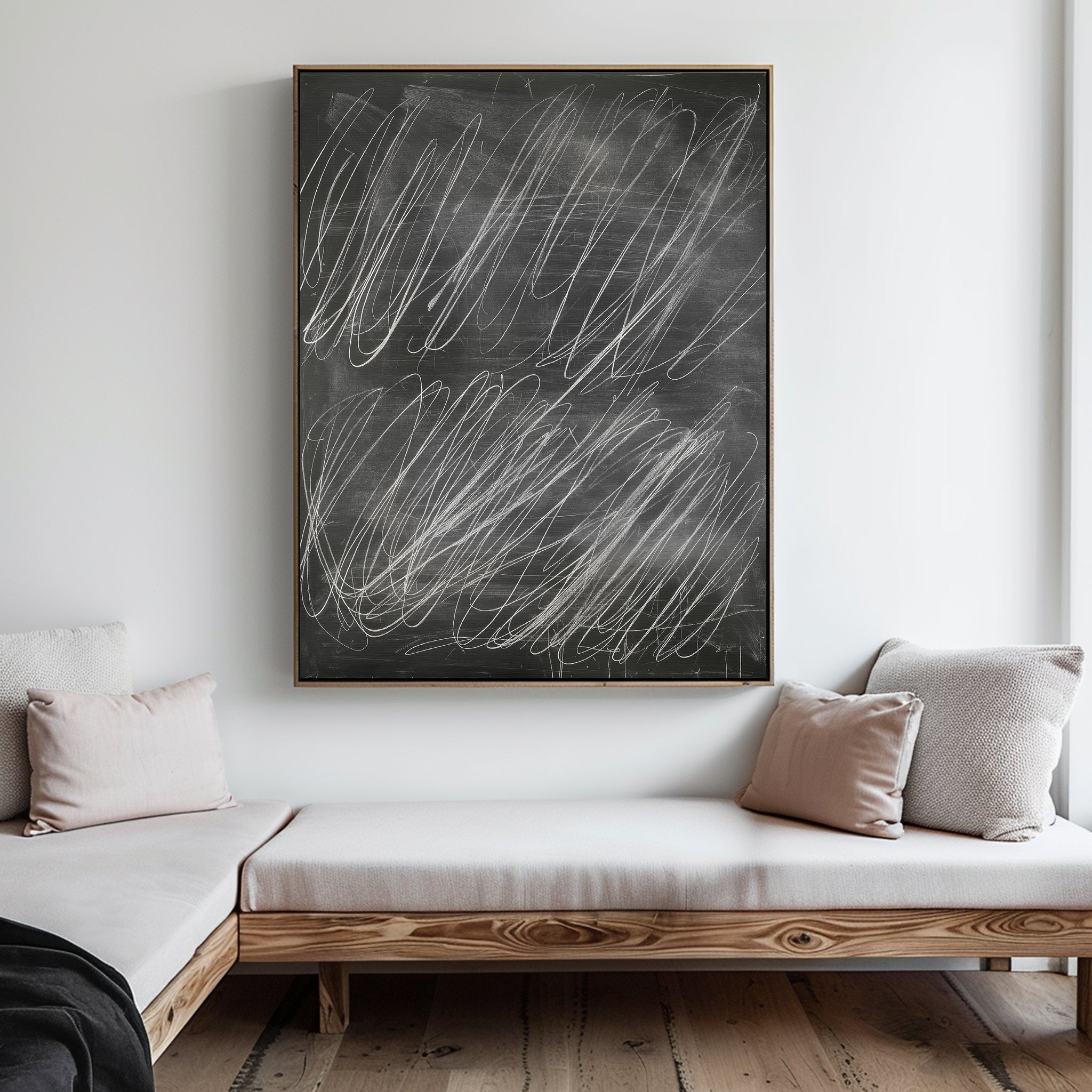 A minimalist living room with light wood benches and neutral cushions, featuring the Echoes in Chalk Abstract Canvas Art—large wall art resembling a chalkboard adorned with irregular white chalk scribbles.