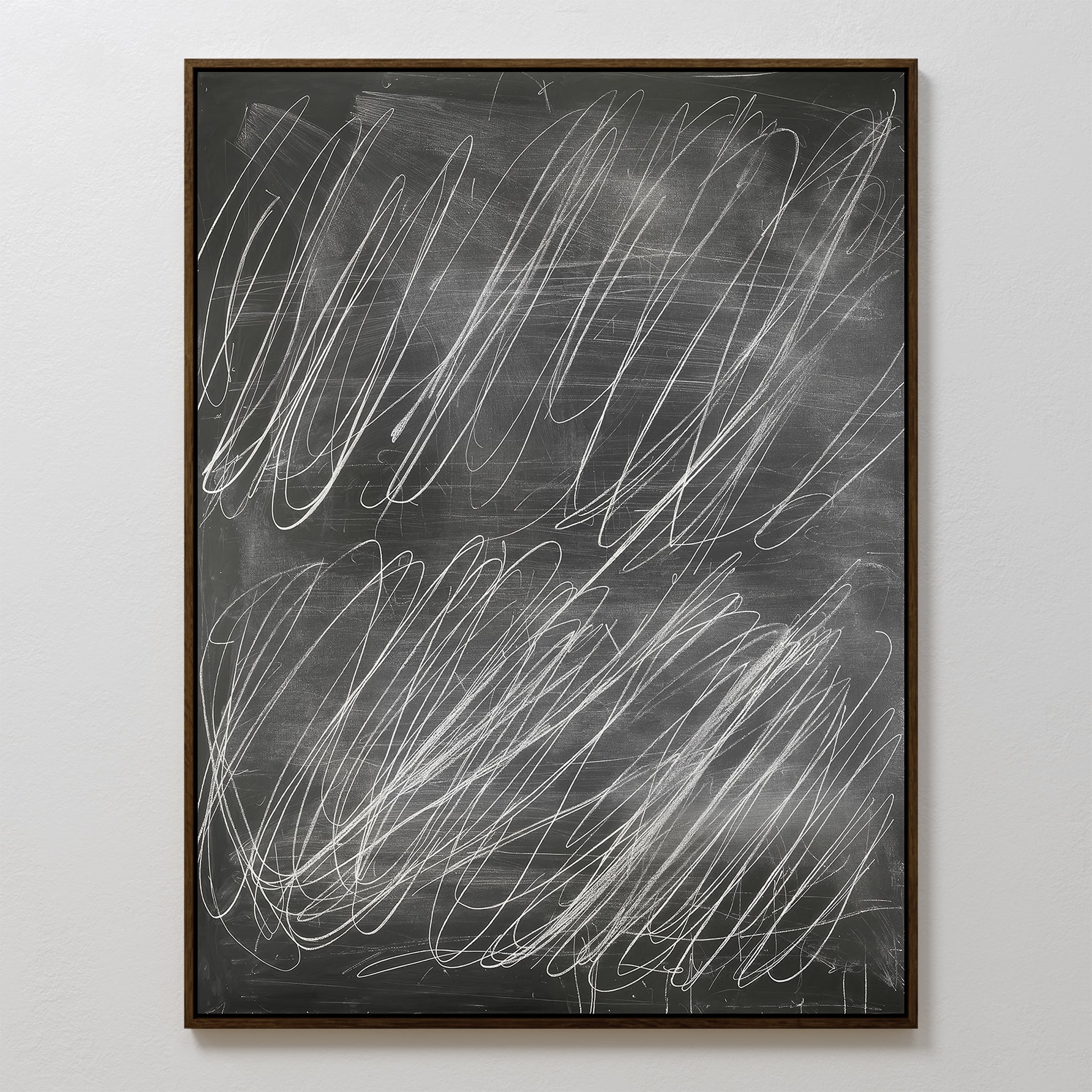 The Echoes in Chalk Abstract Canvas Art features random white chalk scribbles on a blackboard surface. Framed in dark brown against a plain white wall, its minimalist style creates a striking and unique visual contrast for any space.