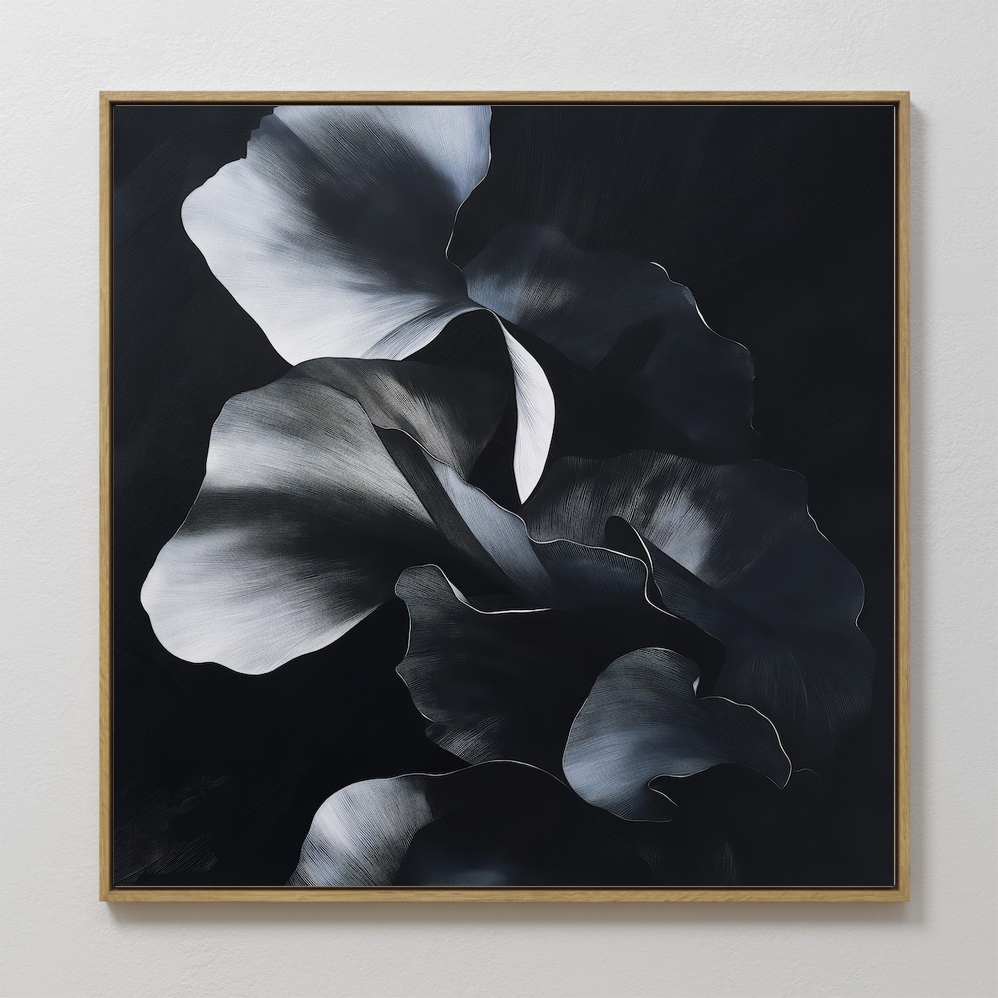 The Nocturnal Bloom Abstract Canvas Art showcases overlapping black, gray, and white floral petals on a dark background, elegantly framed and displayed on a white wall.