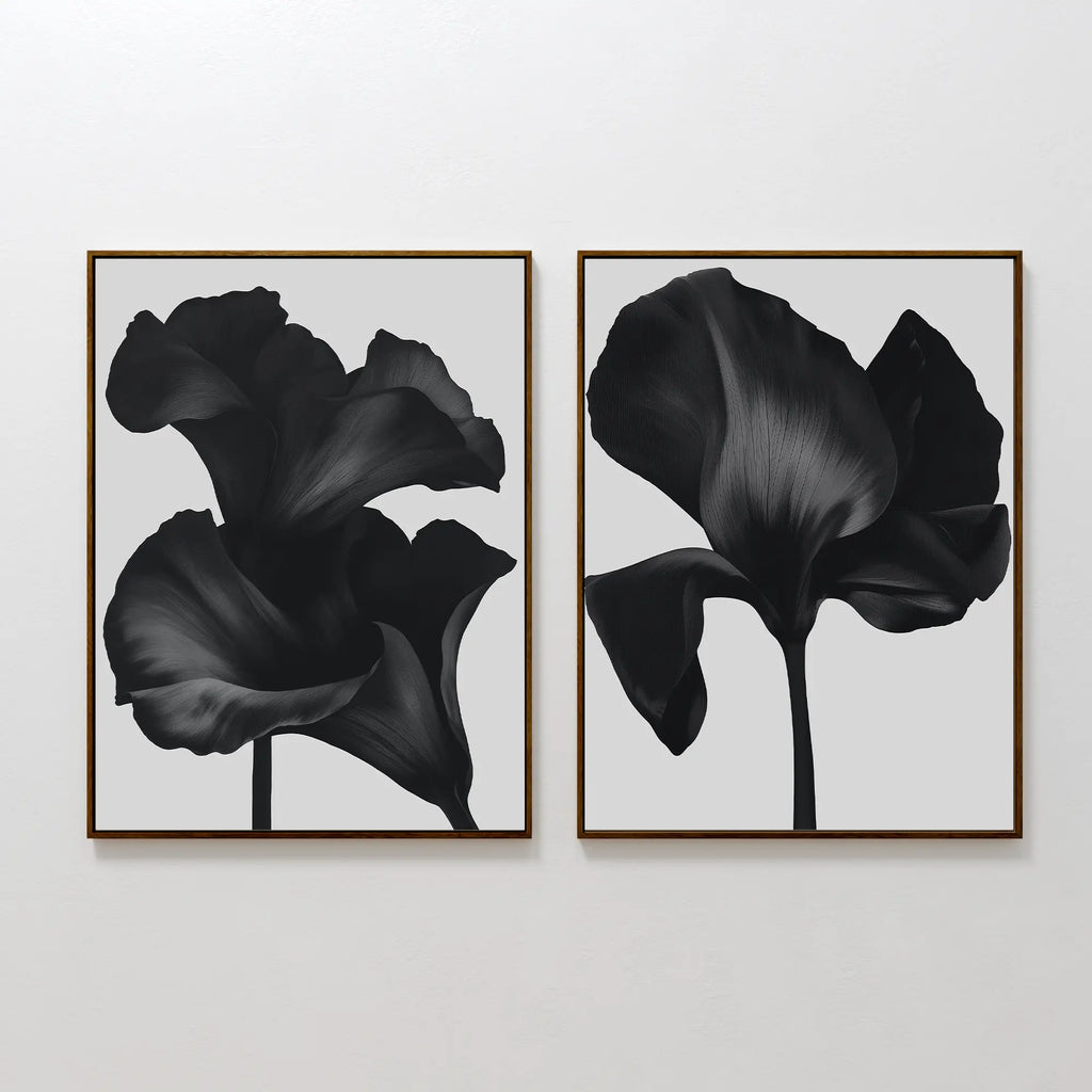 The Noir Bloom Set of 2 features framed black floral prints with detailed single blooms on light gray backgrounds, hung side by side—perfect contemporary wall art for any modern space.