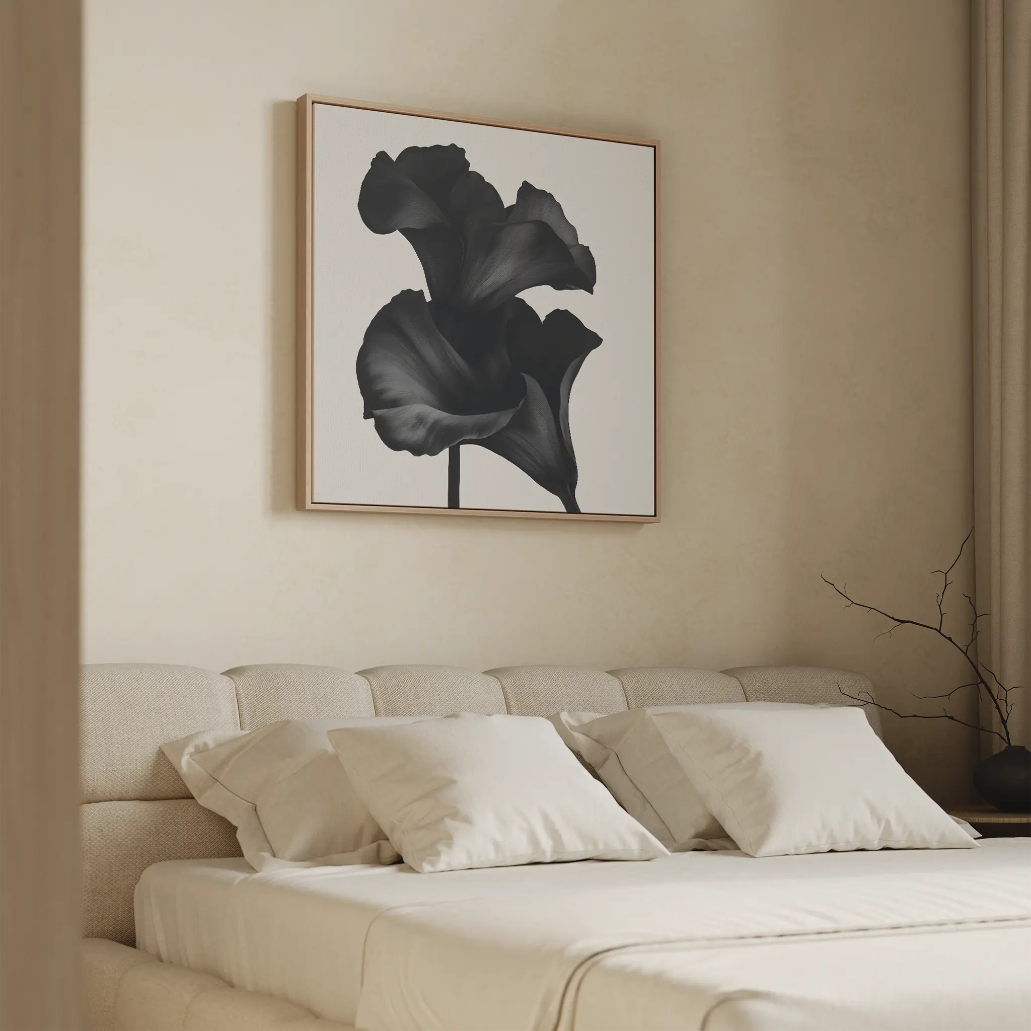 A modern bedroom features a beige upholstered bed with cream bedding and four pillows. Above the bed hangs the Noir Bloom Canvas Art - Square, showcasing a black flower. A minimal branch in a vase rests on the nightstand.